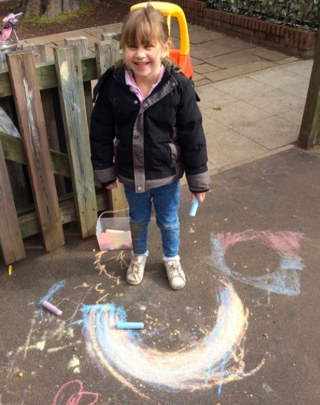 nursery girl standing in playground holding a piece of chalk