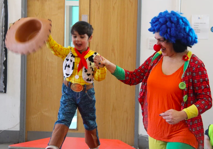 Women holding boys hand as he walks wearing fancy dress for purim