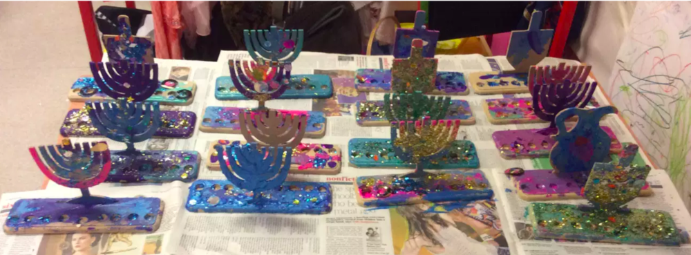 rows of menorahs or chanukiahs made of clay to celebrate hanukah at woodside gan nursery